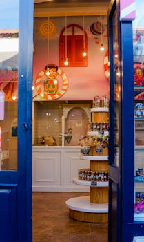 A vibrant candy shop interior with a whimsical mural and pendant lights, viewed through an open blue door.