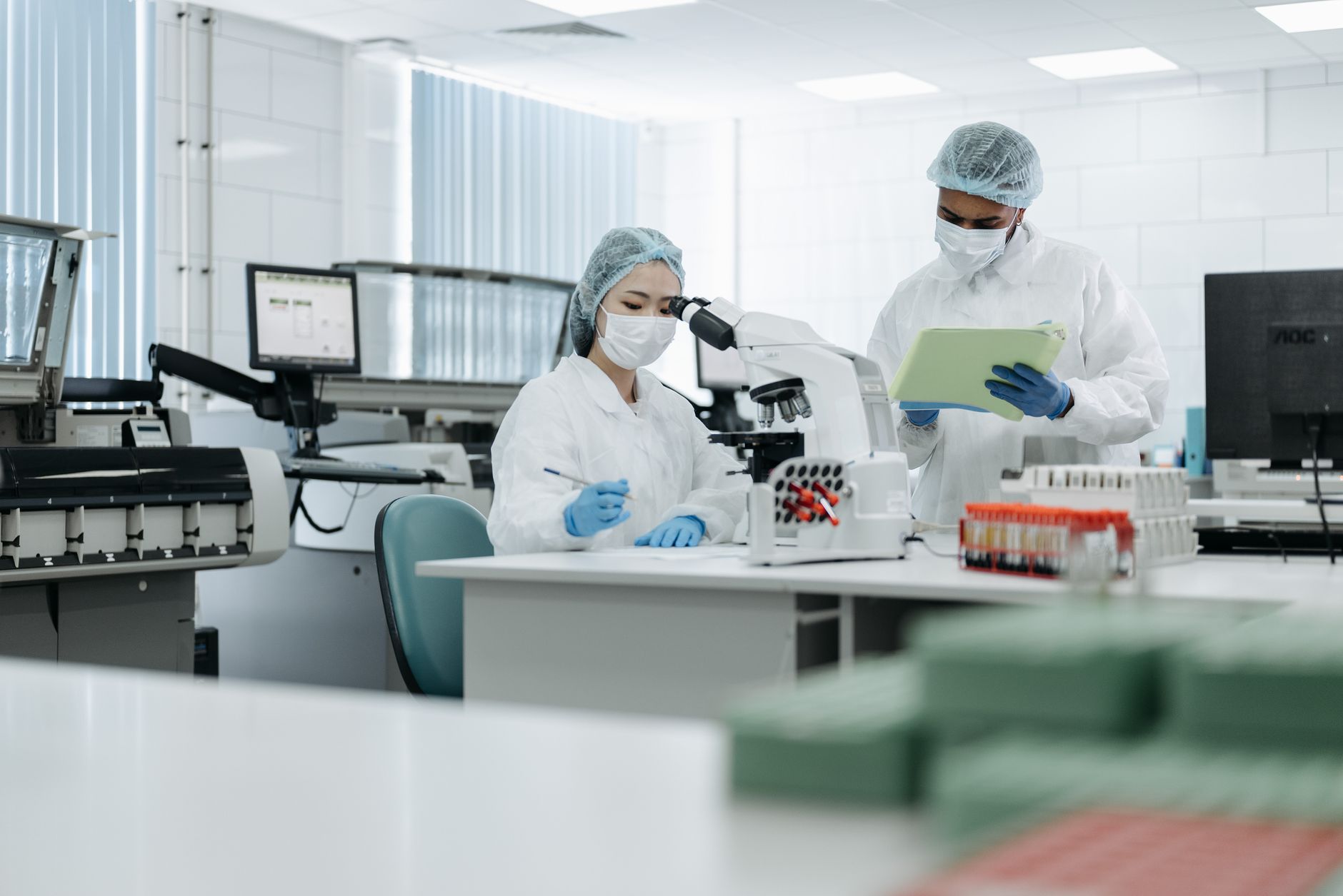 Researchers wearing protective gear analyze samples in high-tech laboratory setting.