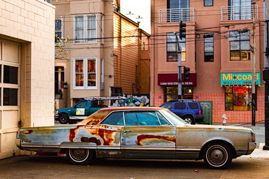 Rusty vintage car parked in San Francisco's colorful cityscape, showcasing urban charm.