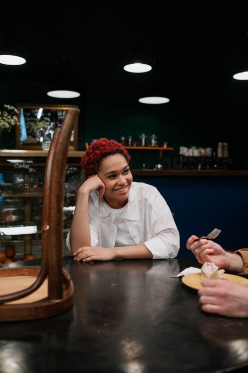 Free Smiling woman enjoying a warm conversation in a cozy indoor cafe. Stock Photo
