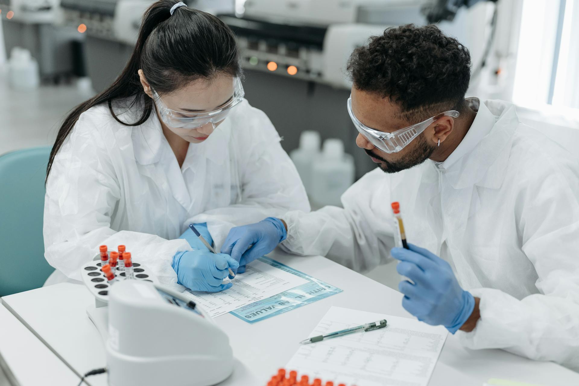 Researchers in protective gear reviewing scientific data in a lab setting.