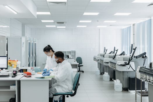 Scientists in a laboratory analyzing samples with advanced equipment and protective gear.