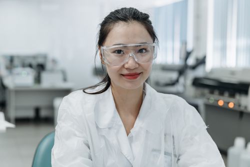 Free Smiling female scientist wearing safety goggles in a modern laboratory. Stock Photo