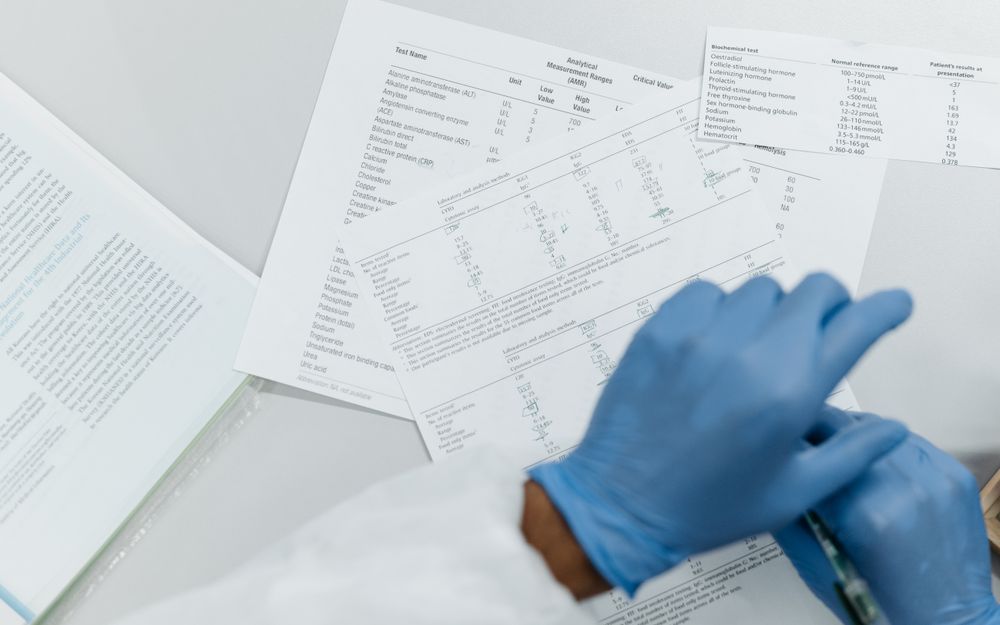 Gloved hands reviewing printed lab test results