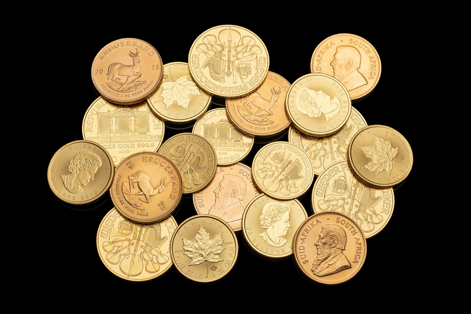 Assorted gold coins showcasing different currencies and designs isolated on a black background.