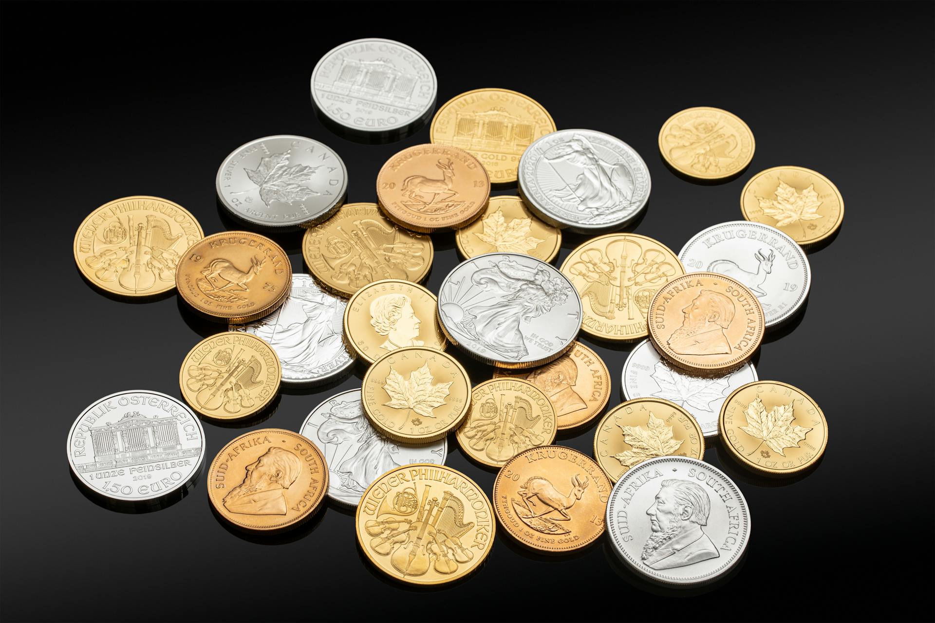 Close-up of assorted coins in silver, gold, and copper on a black background, showing various currencies and denominations.