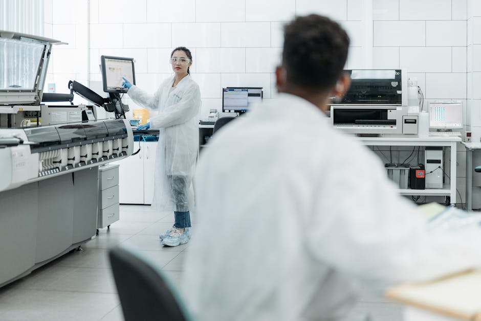 Scientists in a lab environment using monitors and wearing safety gear.