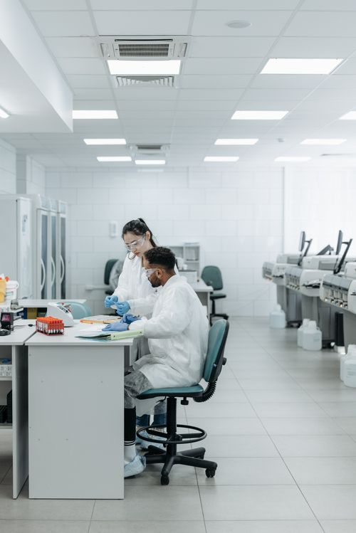 Free Two scientists in lab coats collaborate on experiments in a modern laboratory setting, analyzing data and samples. Stock Photo