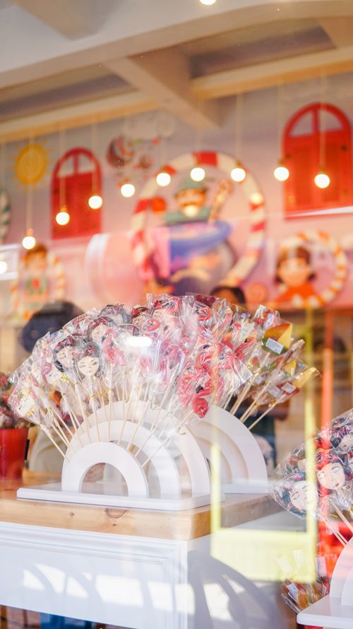 Free A colorful display of assorted lollipops in a candy shop window with ambient reflections. Stock Photo