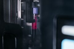 A detailed view of a blood sample test tube inside a laboratory machine, highlighting medical research.