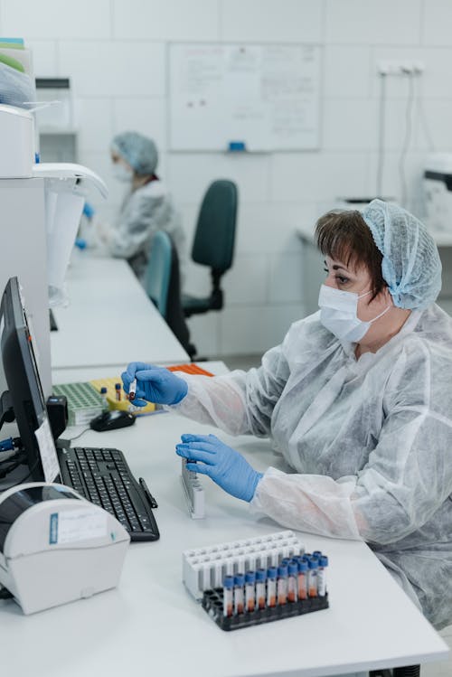 Woman in White Protective Suit Checking Samples 