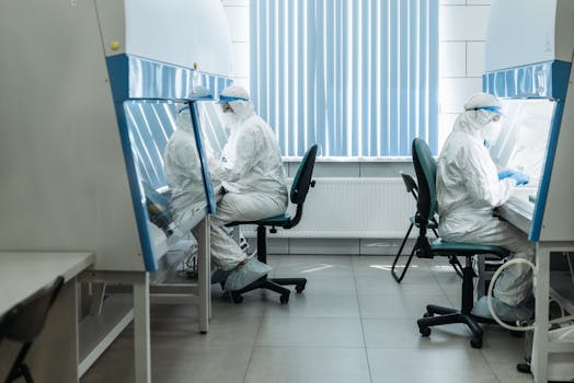 Scientists in protective suits working in laboratory cleanroom, conducting experiments.