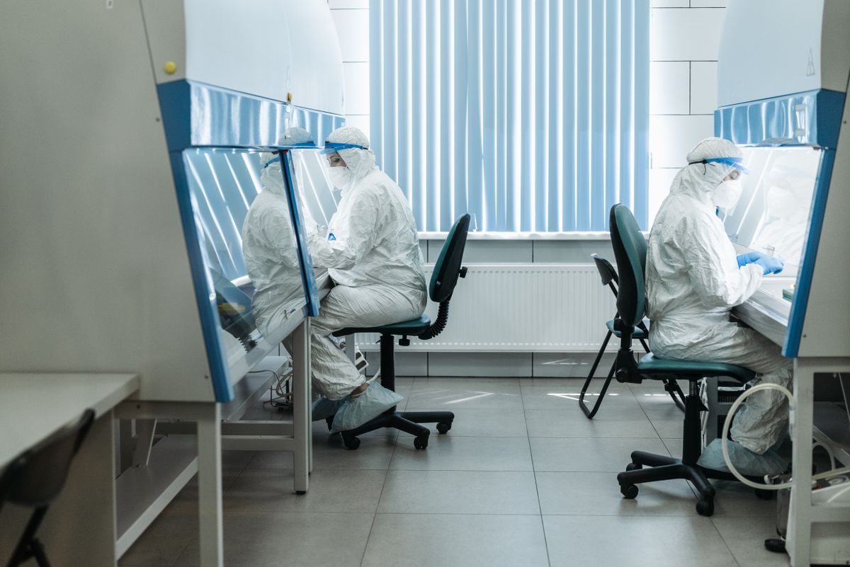 Scientists in protective suits working in laboratory cleanroom, conducting experiments. Illustrative editorial photograph.