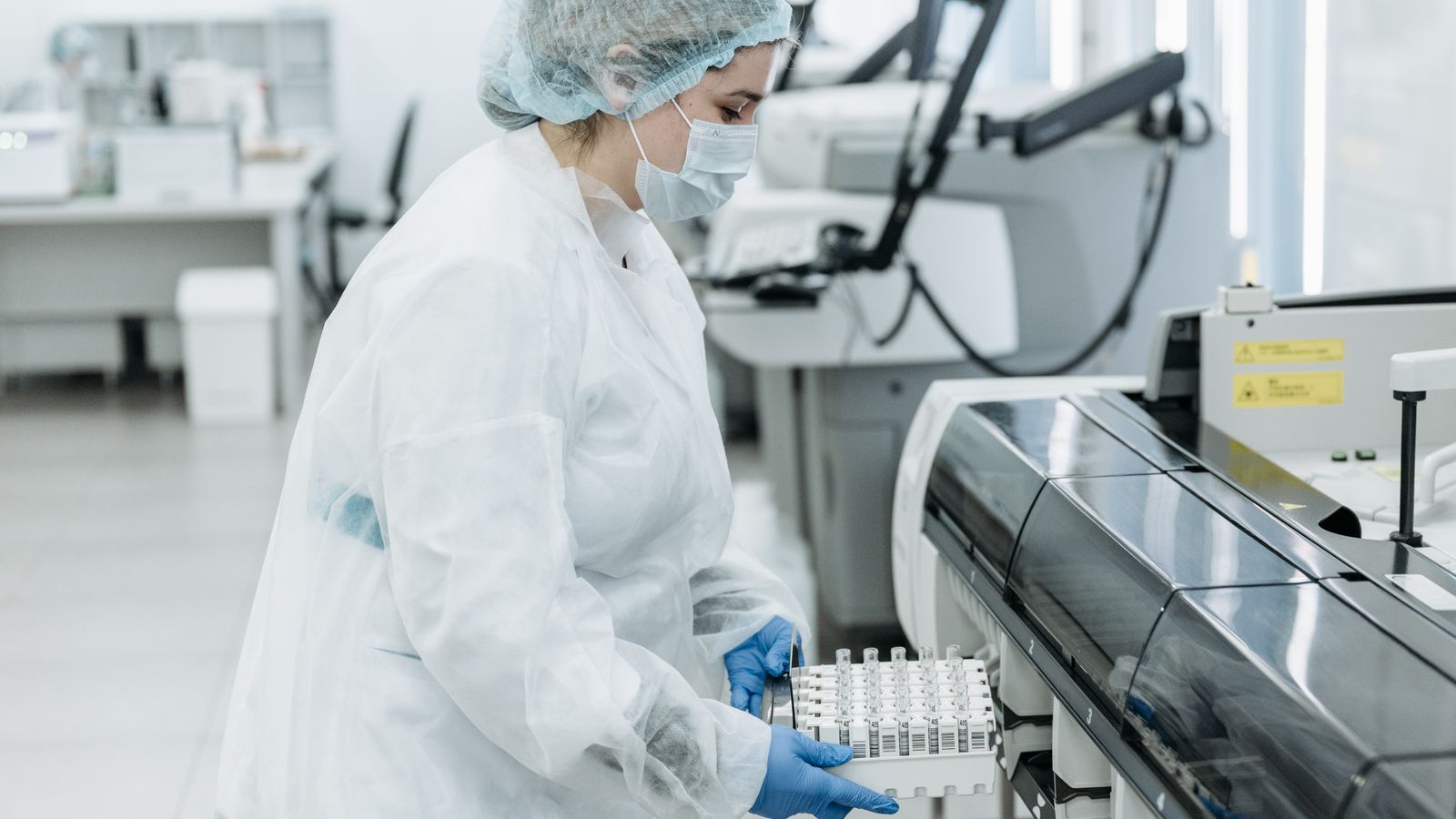 Laboratory scientist in protective gear working with medical samples.
