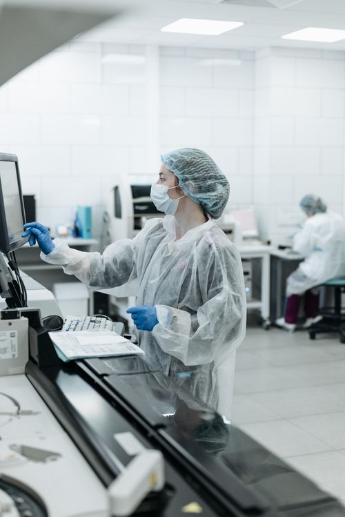 Free Female scientist in a sterile lab environment working on data analysis using a touchscreen. Stock Photo