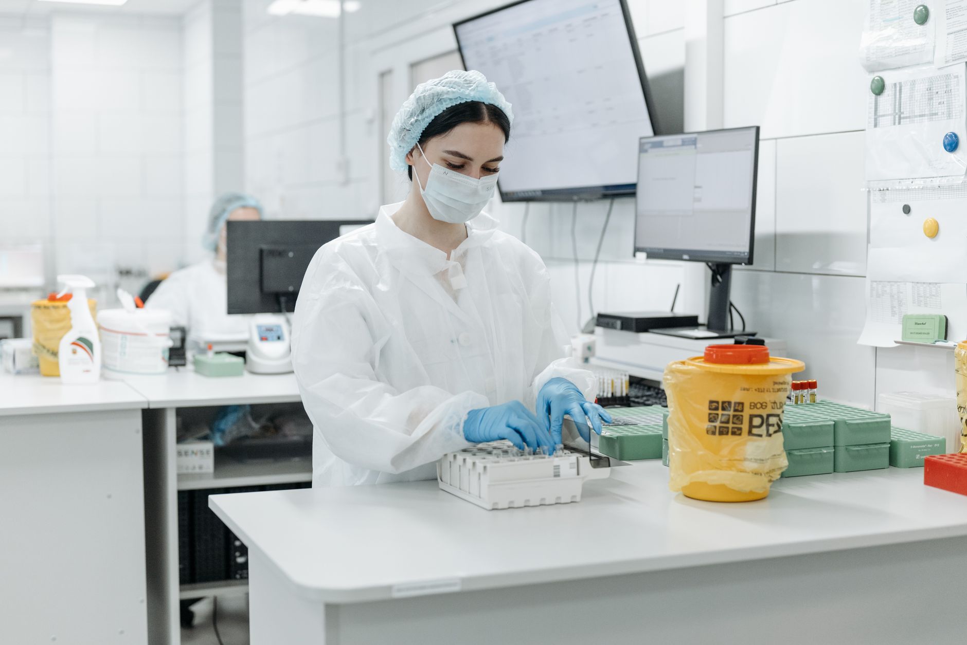 Female scientist in lab coat working with samples in a laboratory environment.