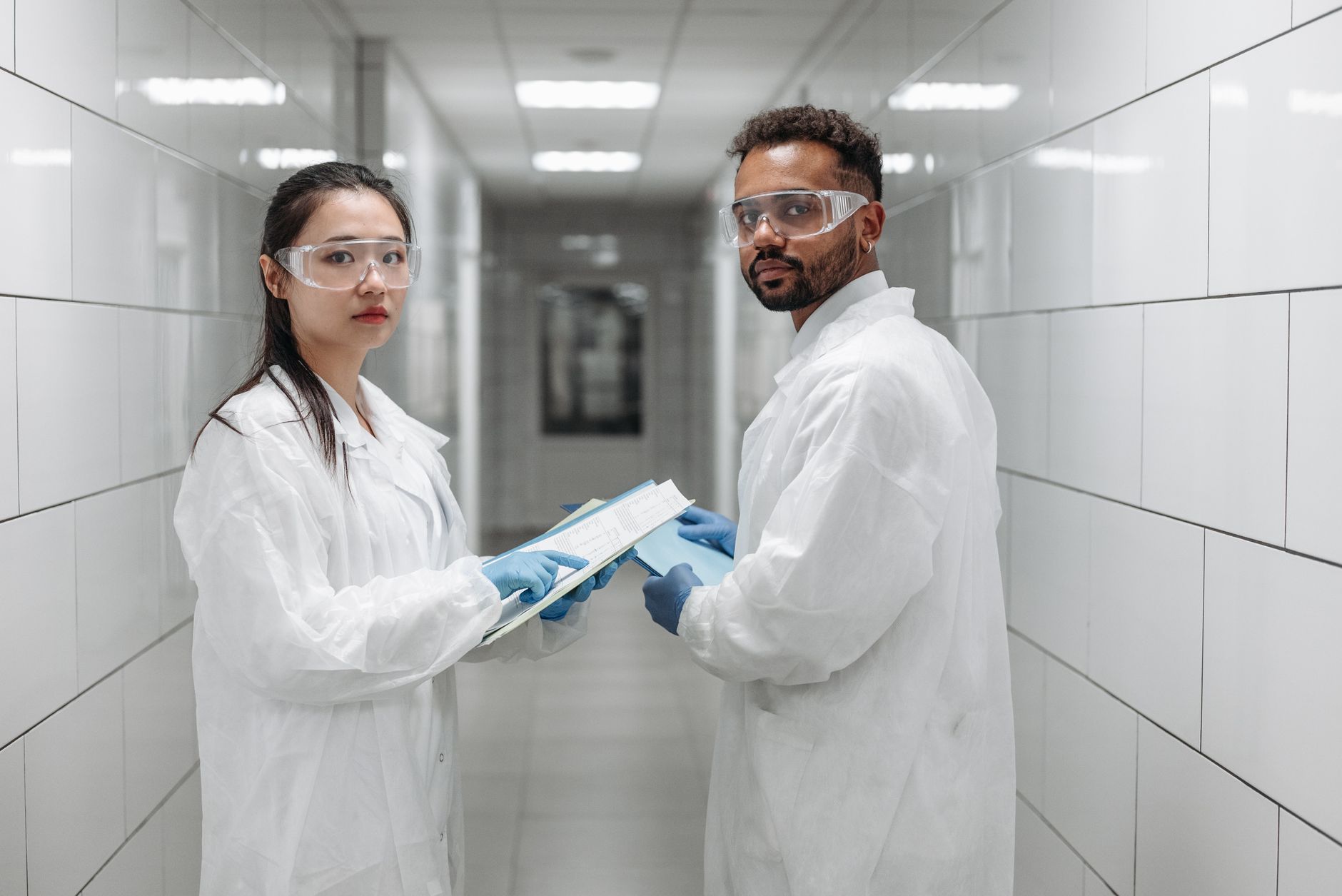Two scientists in protective gear reviewing data in a laboratory setting.