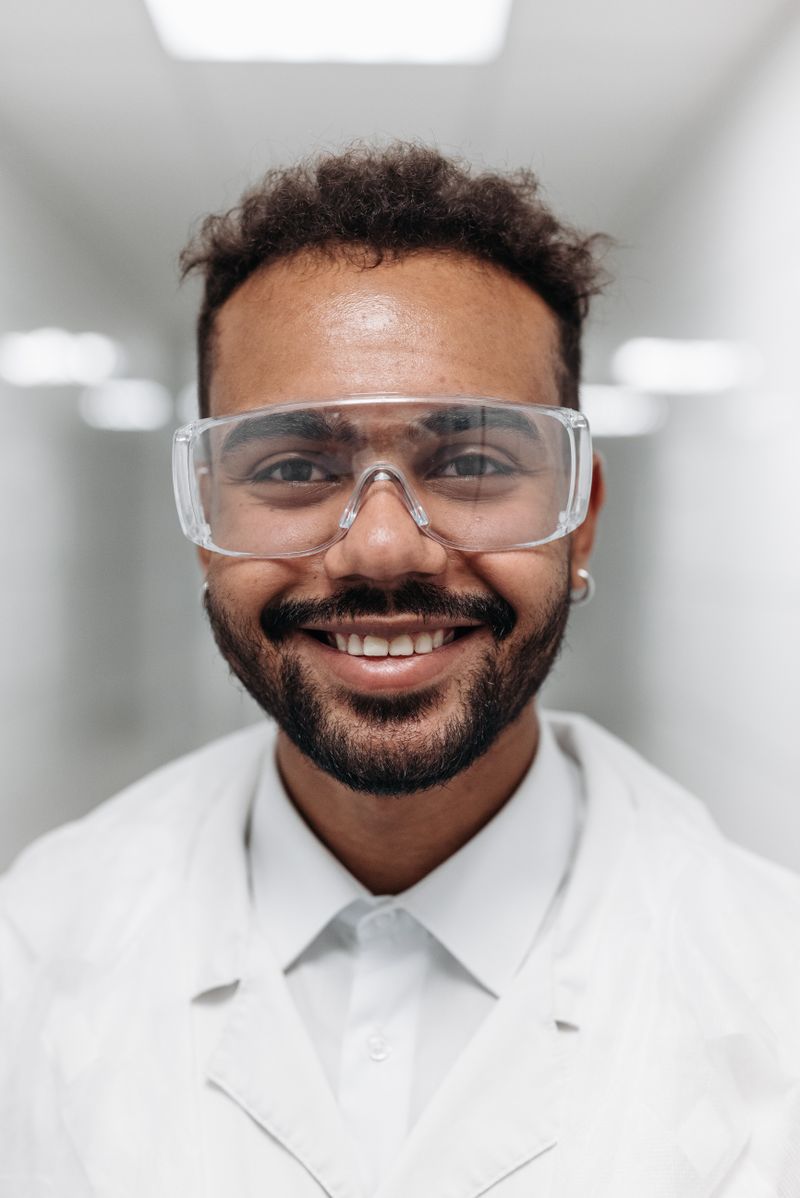 Portrait of Andre Mitchell, smiling, in safety glasses and a lab coat