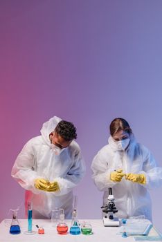 Two scientists working in a lab with protective gear and laboratory equipment.