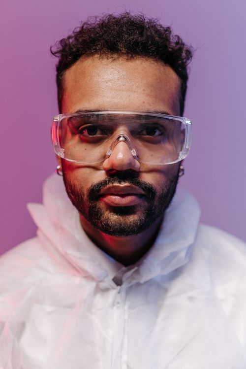 Free Close-up of a scientist wearing protective goggles and lab coat with a colored background. Stock Photo