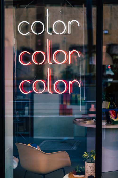 Free Bright neon 'color' sign in a stylish store window, showcasing trendy decor items. Stock Photo