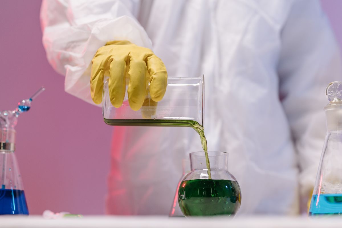 Scientist pouring green liquid sample in biofuel research laboratory