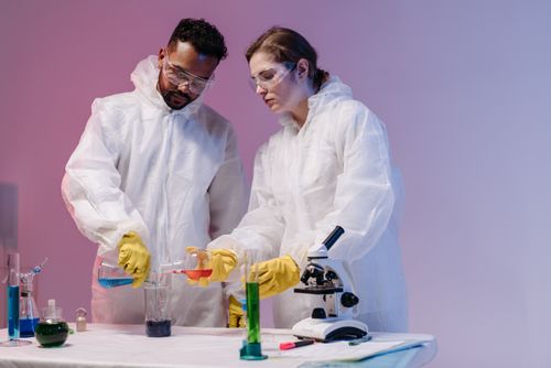 Free Two scientists in white lab coats and goggles conducting experiments with test tubes and beakers. Stock Photo