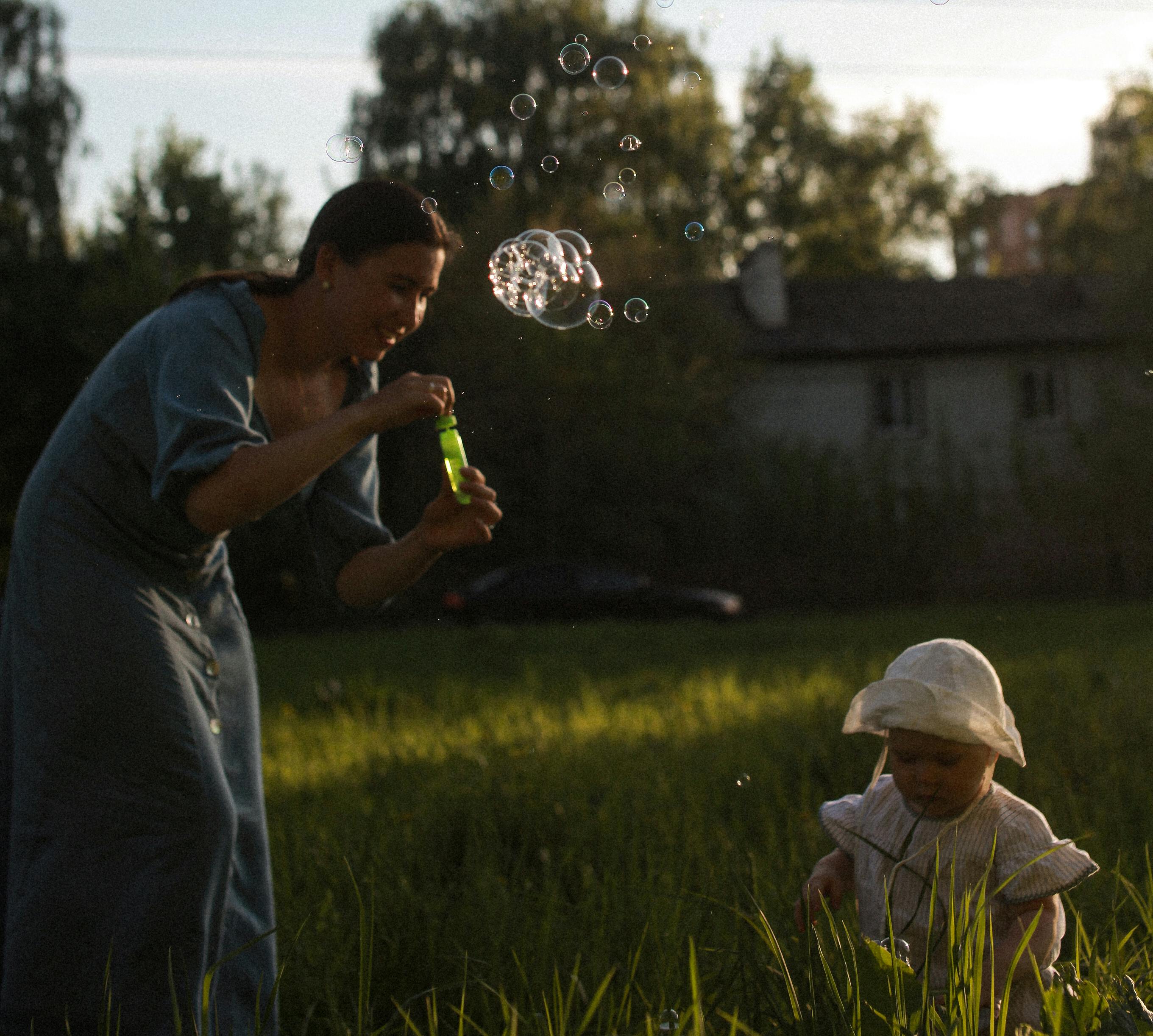 woman playing soap bubbles with her baby