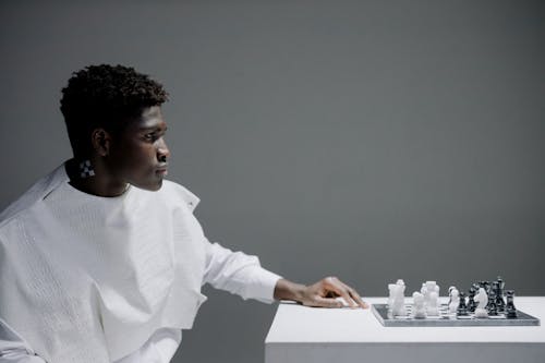 Man in White Sweater Playing Chess 