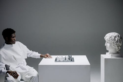 A Man Playing Chess Against a Head Statue
