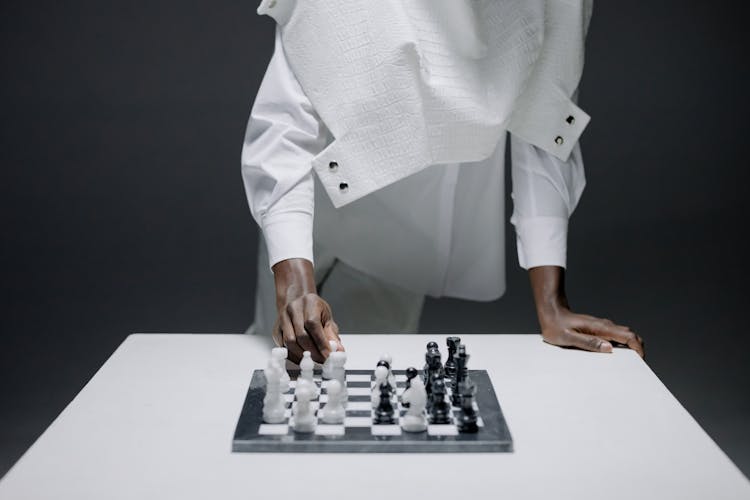 A Person In White Long Sleeves Playing Chess