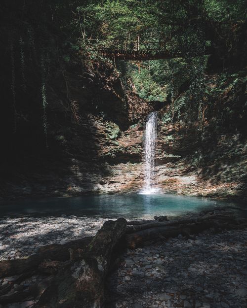Free A serene waterfall cascades into a pond in a lush forest in Эстосадок, Russia. Stock Photo