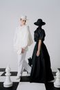 Man in White Dress Shirt and Black Skirt Standing Beside Black and White Chess Piece
