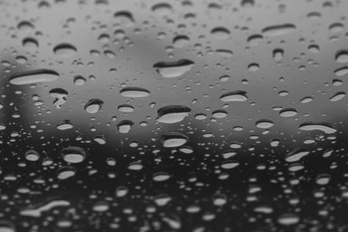 Free Black and white image of raindrops on a window creating an abstract and moody atmosphere. Stock Photo