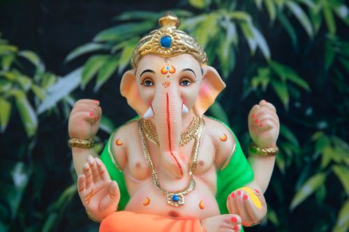 Free Colorful Ganesha statue set against lush green foliage, symbolizing Hindu spirituality. Stock Photo