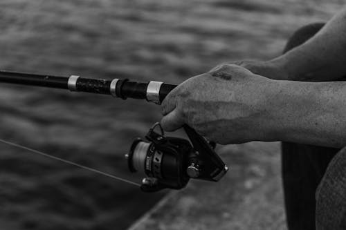 Grayscale Photo of Person Holding a Fishing Rod