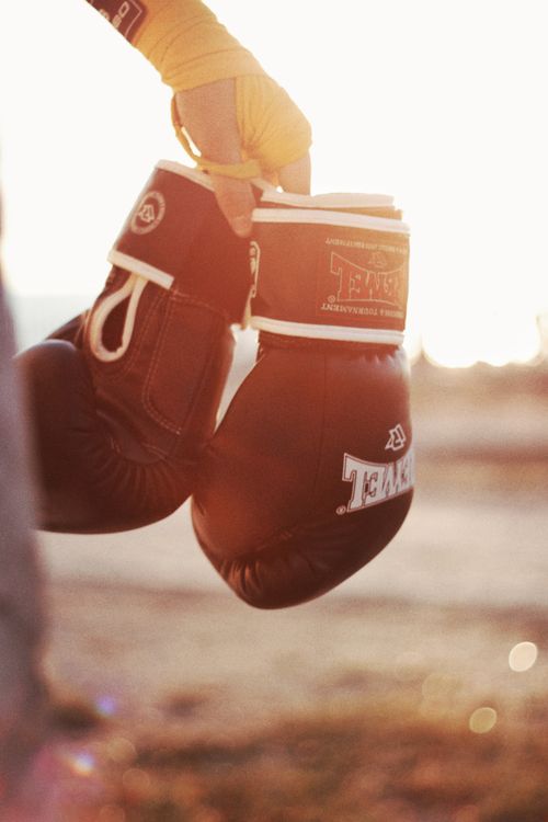 Free Pair of boxing gloves held outdoors with warm sunlight, symbolizing sports energy. Stock Photo