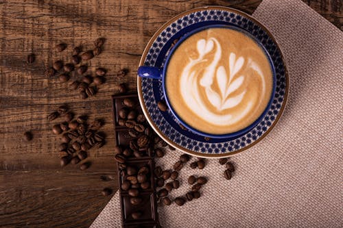 Free Roasted Coffee Beans Beside a Cup of Espresso with Latte Art Stock Photo