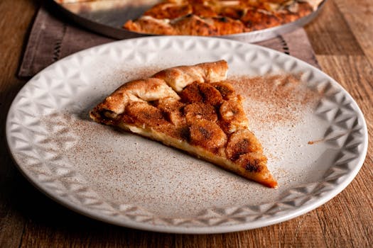 Close-up of a cinnamon sugar apple dessert pizza slice on a white plate.