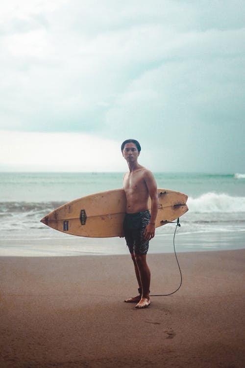 Free Photo of a Topless Man Carrying a Yellow Surfboard Stock Photo