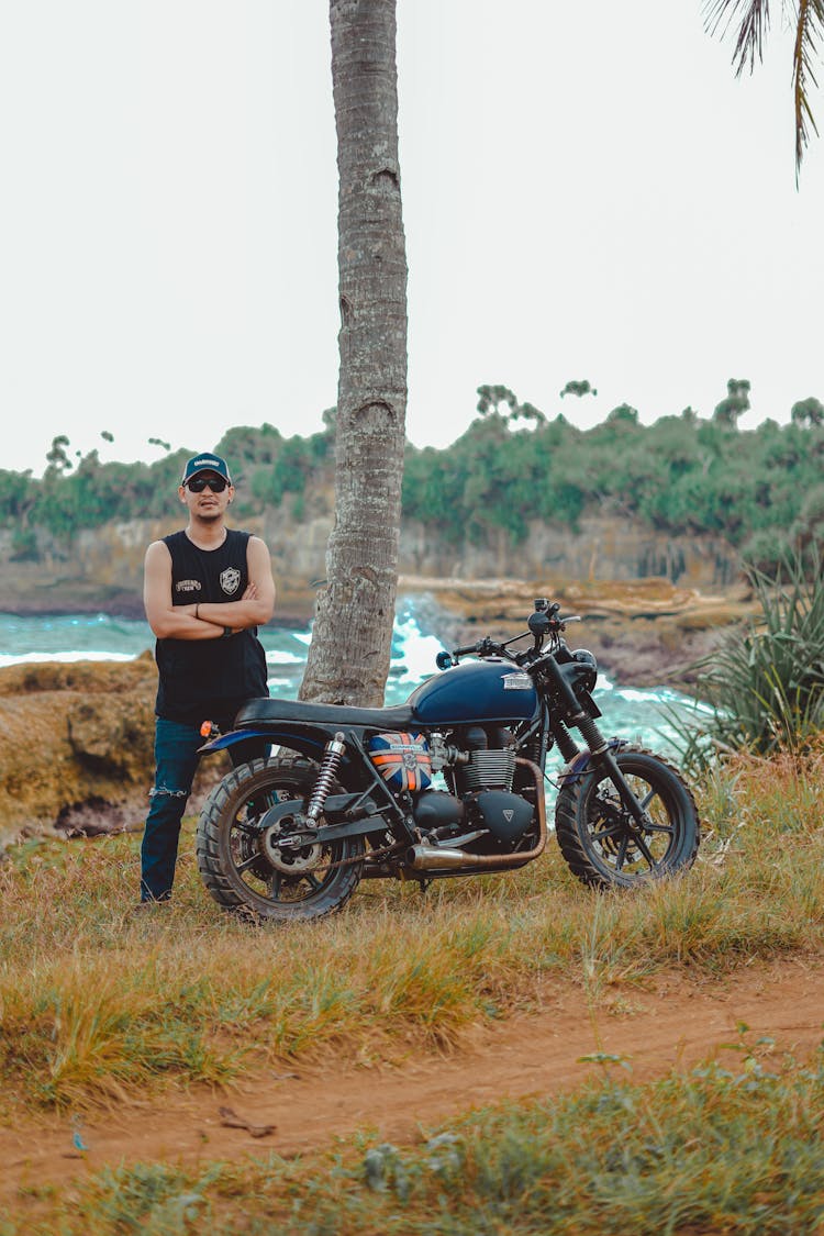 Man In Black Tank Top And Denim Jeans Standing Beside Black Motorcycle