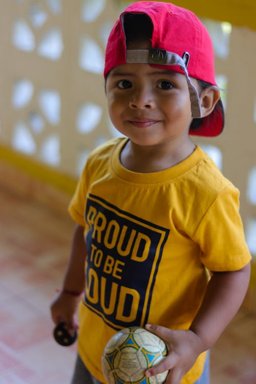 Boy in Yellow Crew Neck T-shirt Wearing Red Cap