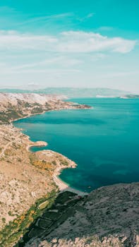 Explore the stunning aerial view of Krk's coastline in Croatia, featuring turquoise waters and rocky shores.