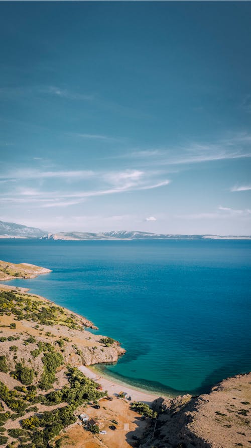 Aerial View of a Sea Beside the Green and Brown Landscape