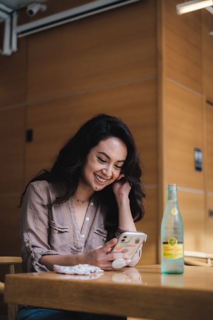 Happy woman sitting indoors, enjoying casual moment with her phone.