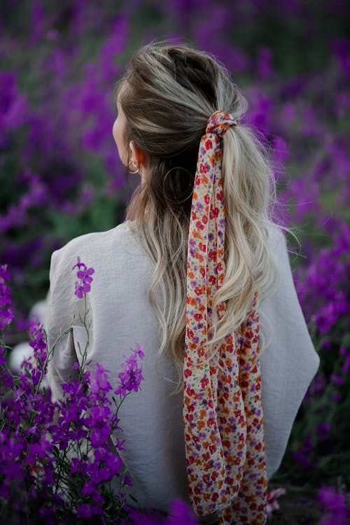 Free Back View of a Tied Hair                           Woman Standing Beside Purple Flowers  Stock Photo