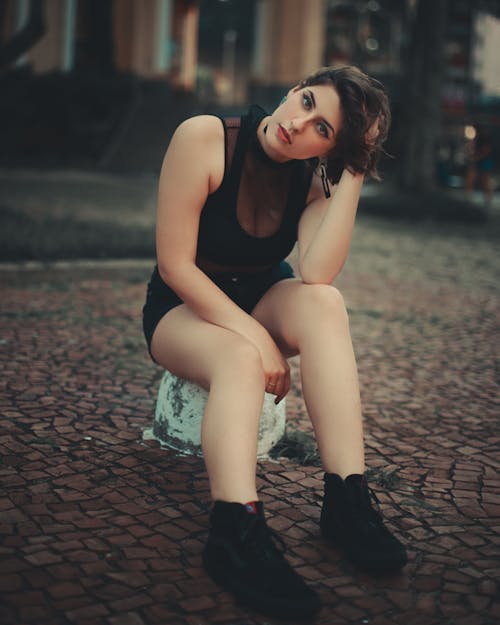 Selective Focus Photo of a Woman Sitting while Touching Her Hair