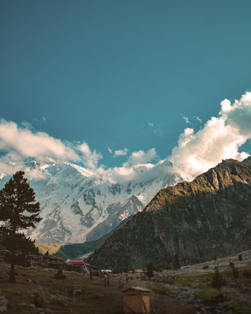 Free Stunning view of a snow-capped mountain range with lush greenery under a clear blue sky. Stock Photo