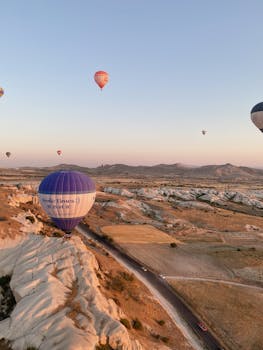 Stunning aerial view of hot air balloons floating over the unique landscapes of Cappadocia, Turkey.