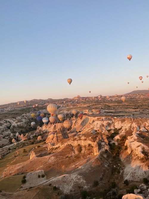 Free Breathtaking view of hot air balloons soaring over Cappadocia's rocky formations at sunrise. Stock Photo